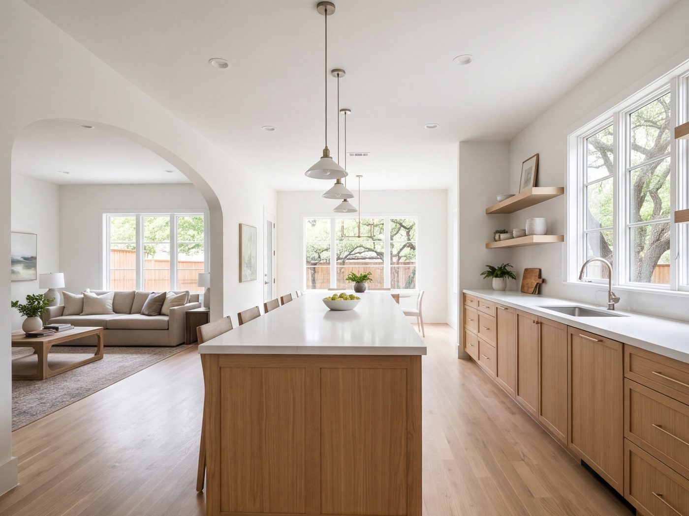 Long galley-style kitchen opened to a family room with a counter and pendant lights